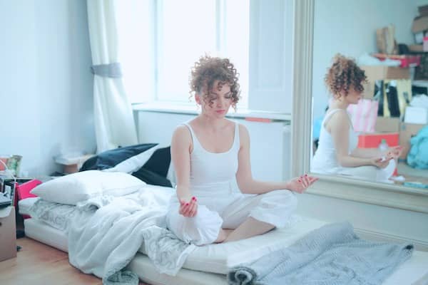 Picture of a white woman sitting in her messy bedroom being edited by AirBrush