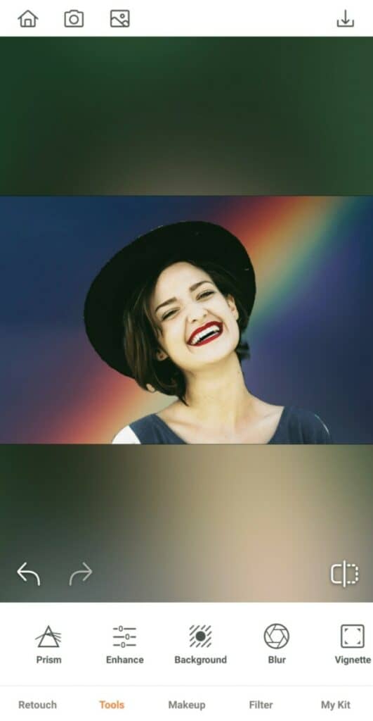 laughing woman wearing a hat in front of a rainbow background