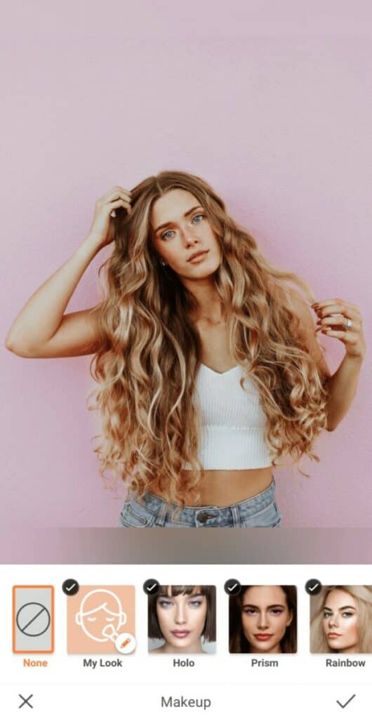 woman with curly blonde hair standing in front of a pink wall