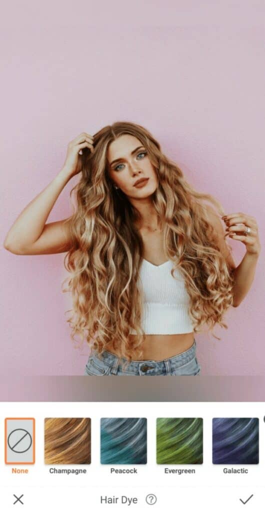 blonde woman in a white top stands in front of a pink wall