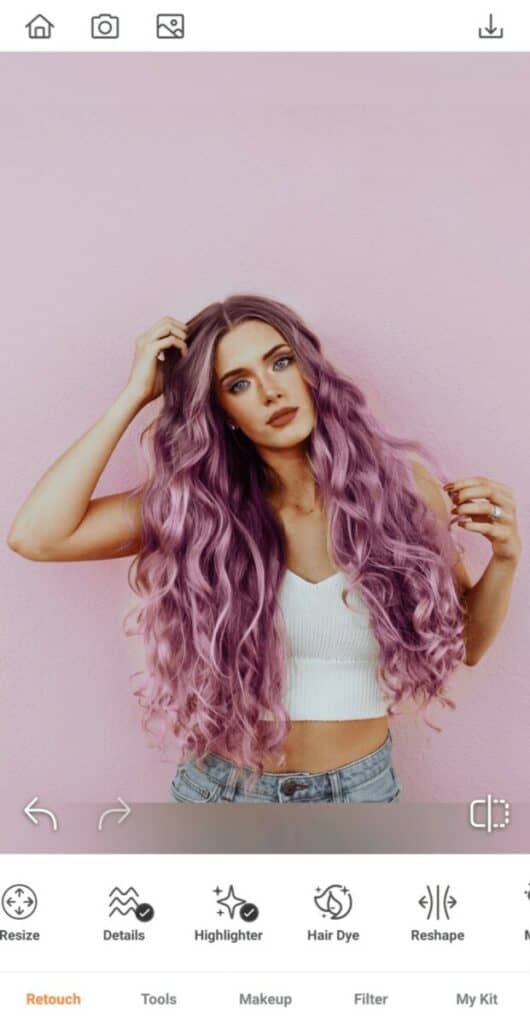 Pride edit of woman with purple hair in a white top stands in front of a pink wall