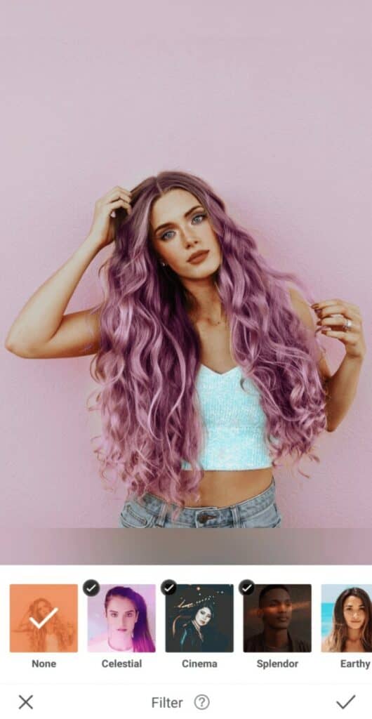 Pride edit of woman with purple hair in a white top stands in front of a pink wall