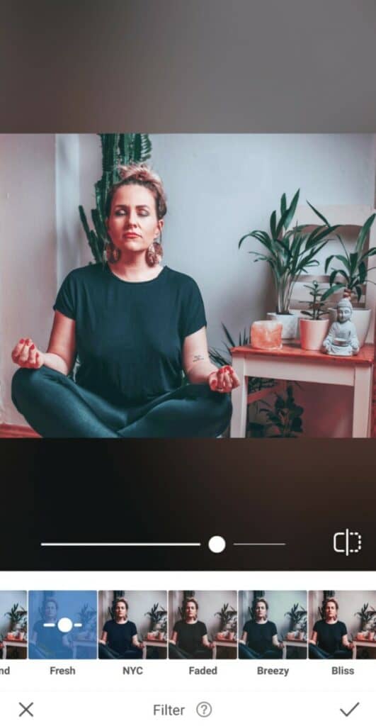 woman sitting and meditating next to plants