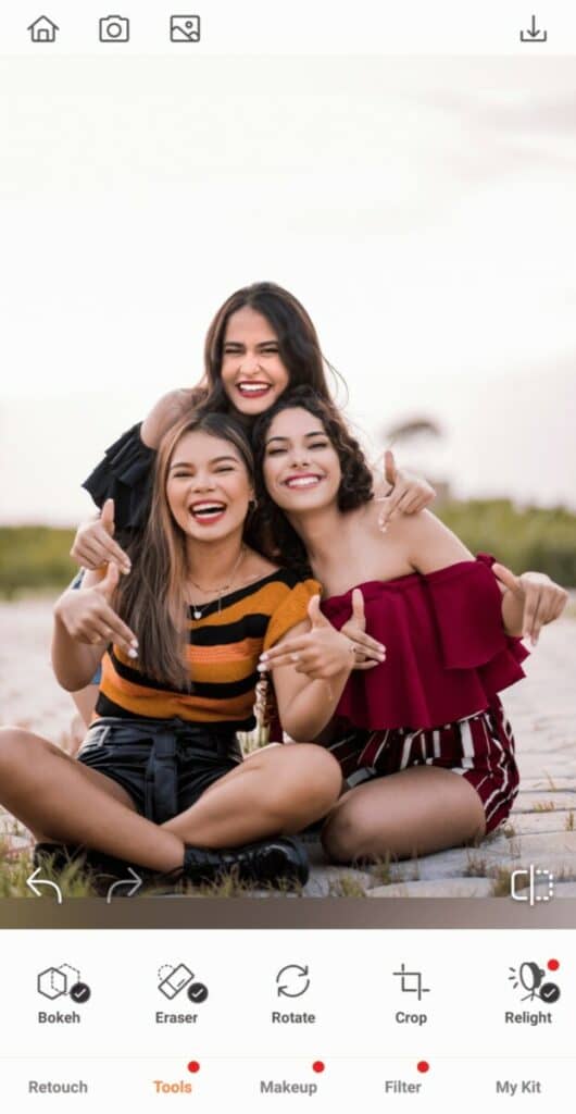 Group photo of three smiling women taking a photo on the beach