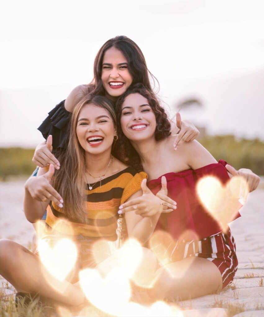 Group photo of three smiling women taking a photo on the beach