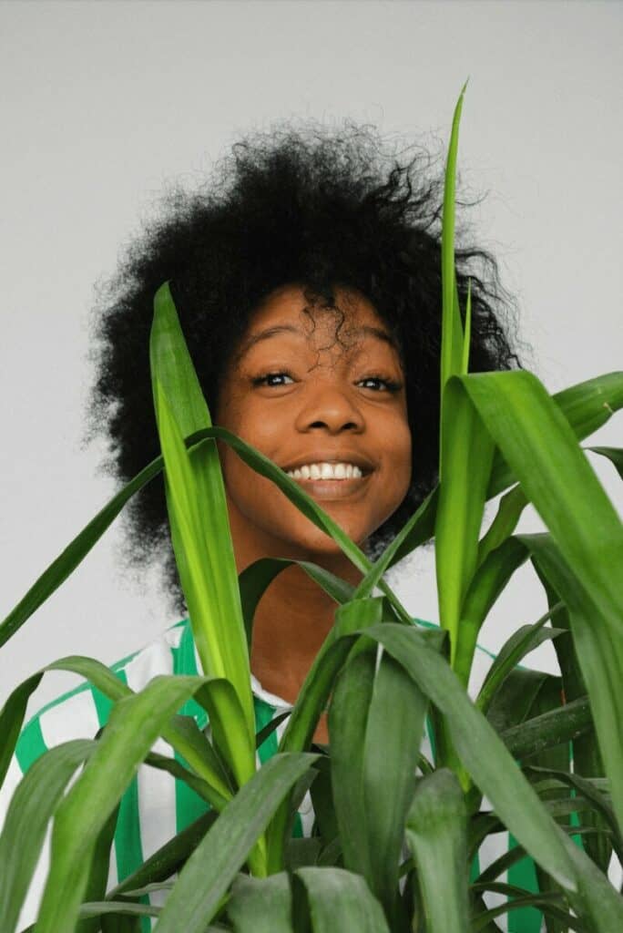 woman with afro standing behind a plant