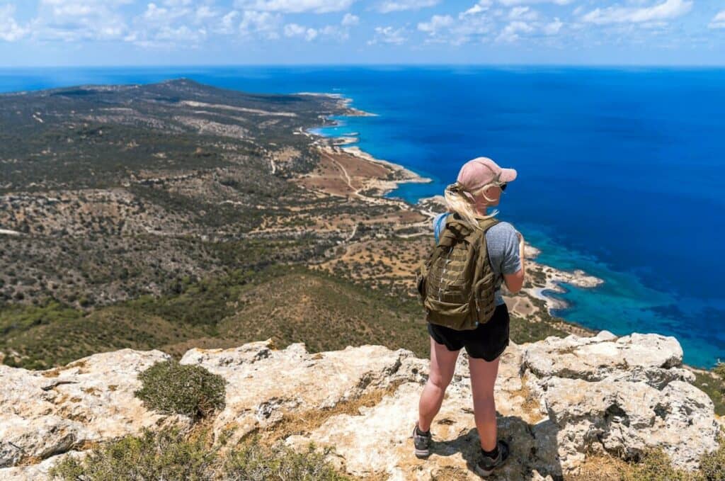 travel photo of woman standing on a rock looking out over an ocean view