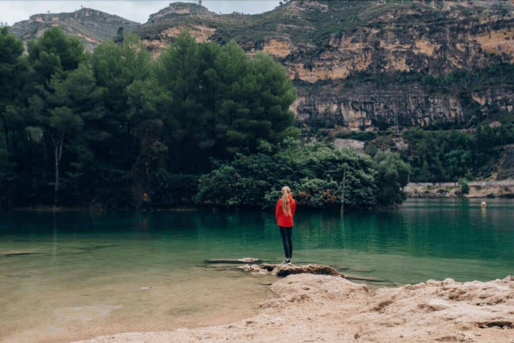 woman standing on the edge of a green lake