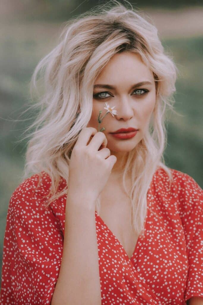 woman with blonde hair holding a flower