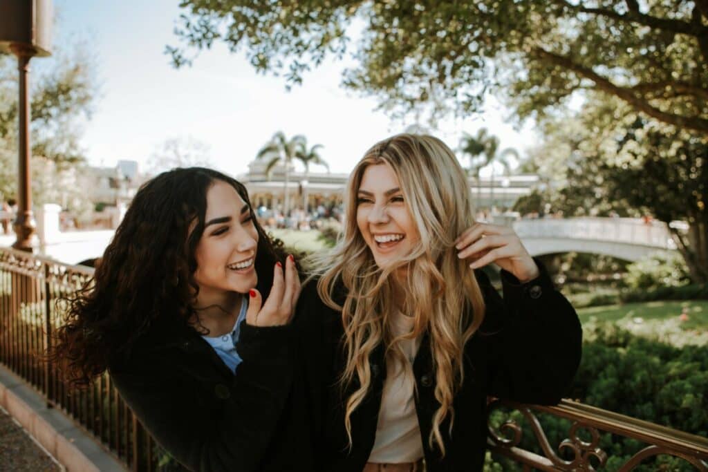 two women laughing, one with black hair and the other with blonde hair