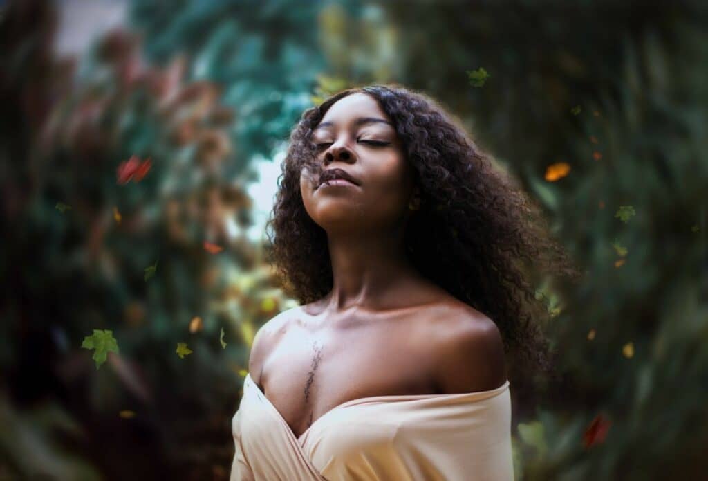 woman wearing an off-the-shoulder top standing in front of a blurred garden scene