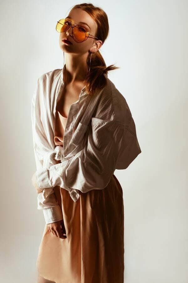 Foto de uma mulher com camisa clara e saia rosa, usando óculos de sol